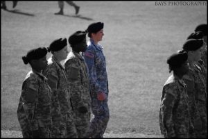 Soldiers lined up in rows in a marching formation. The image is black and white except for PFC Hunniecutt (the author), soldier on the end of the row in the second lane, who is shown in color for emphasis. Photo credit: Bays Photography